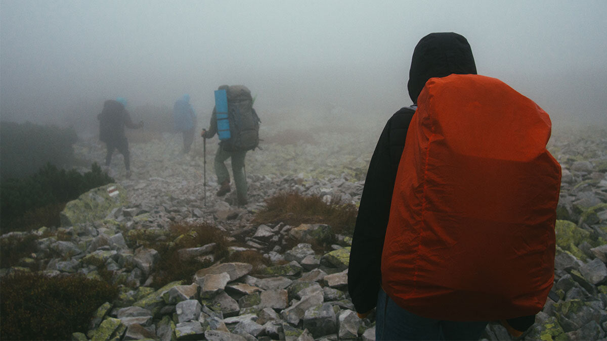 A group of hikers walking through the rain up a mountain.