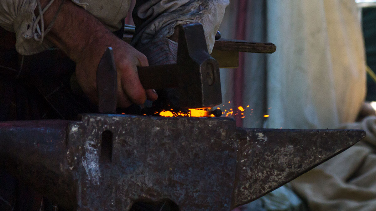 A person working with hot metal on an anvil.