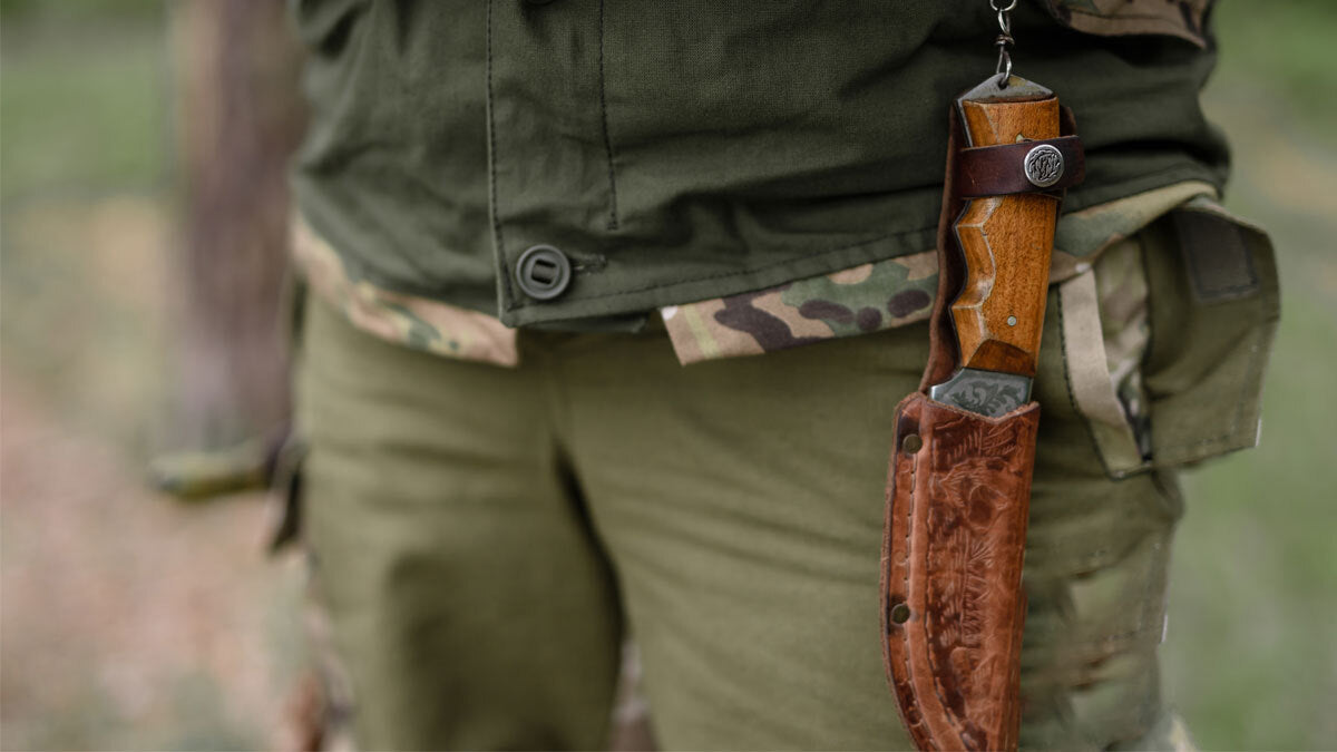 Man in outdoor wear with a knife sheathed and clipped to his belt.