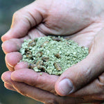Hands holding a pile of small grey firestarter pellets from InstaFire Fire Starter 2-gallon bucket.